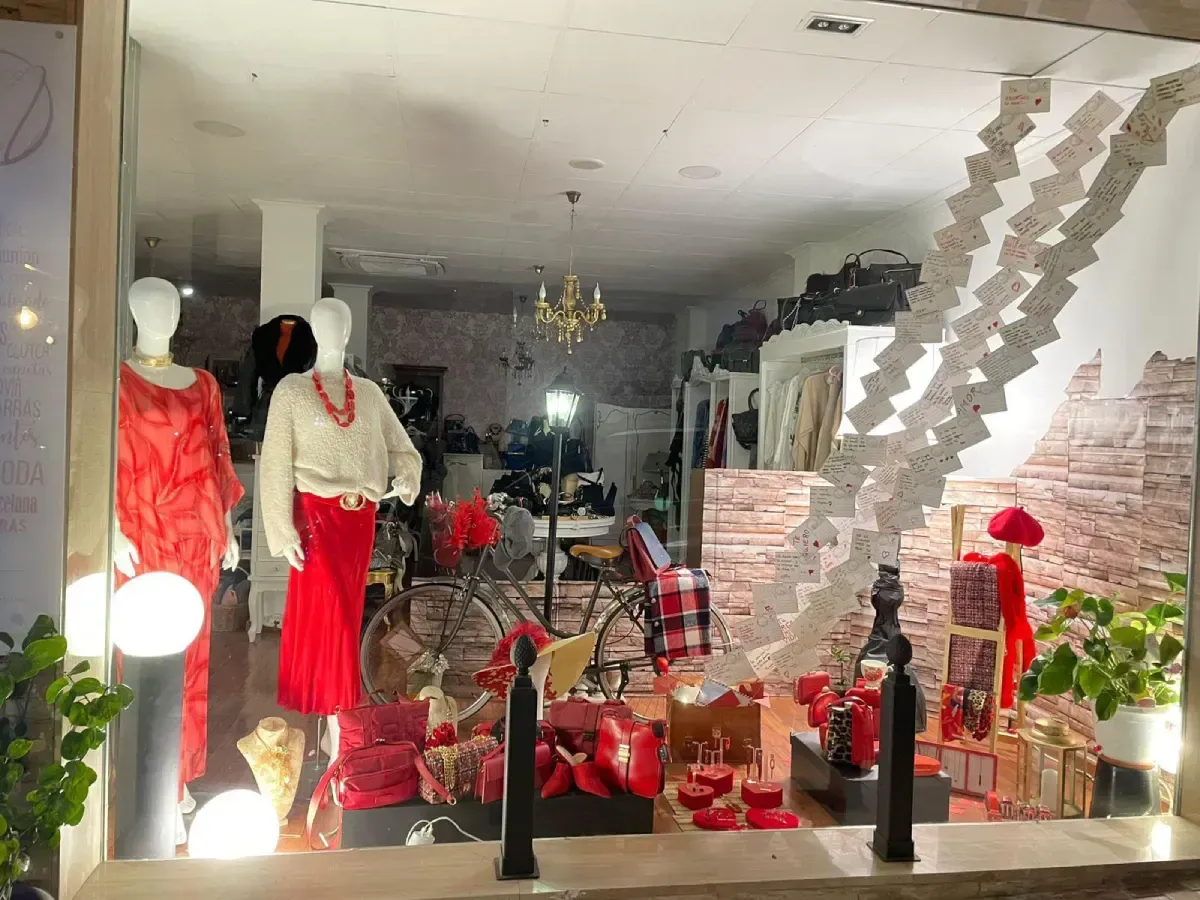 Escaparate con prendas rojas sobre maniquíes, accesorios rojos y elementos decorativos.