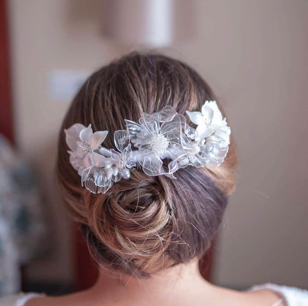Parte posterior de la cabeza de una persona con un moño bajo adornado con un peine floral plateado.
