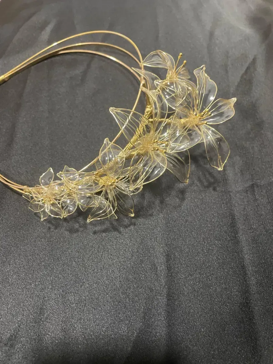 Diadema floral dorada y transparente sobre una superficie oscura.