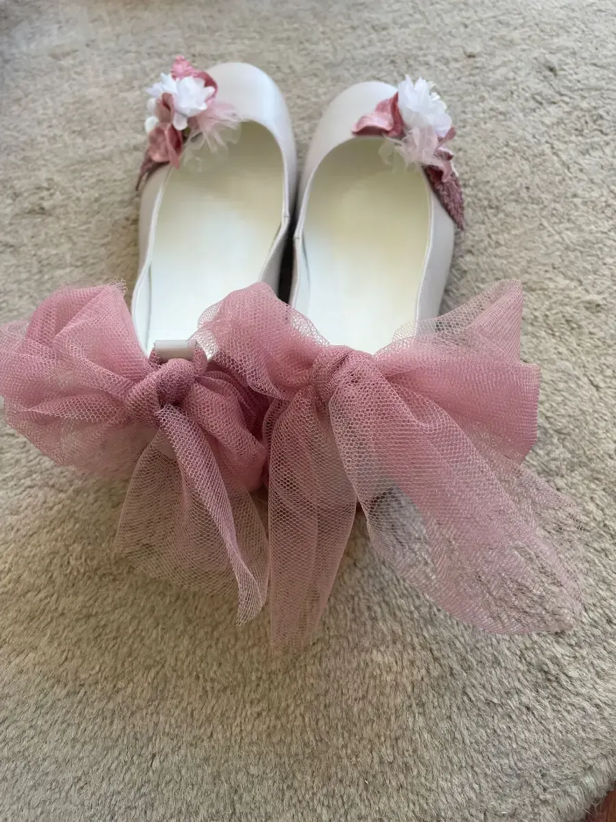 Par de zapatillas de ballet blancas con detalles de tul rosa y flores.
