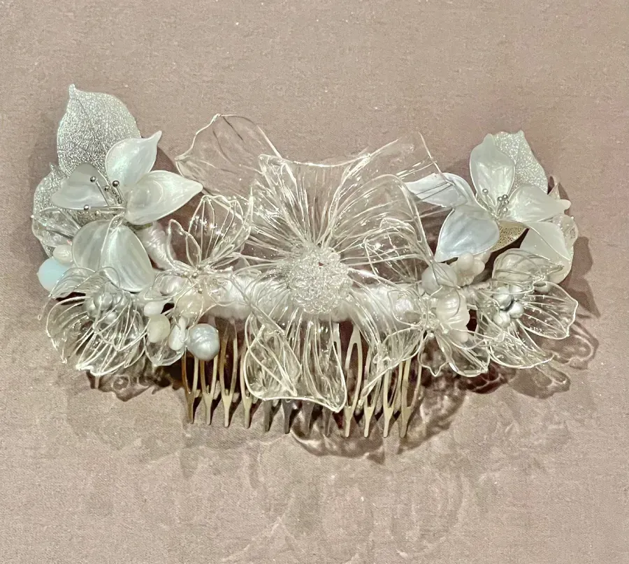 Peineta floral transparente y brillante sobre una superficie de color rosa claro.