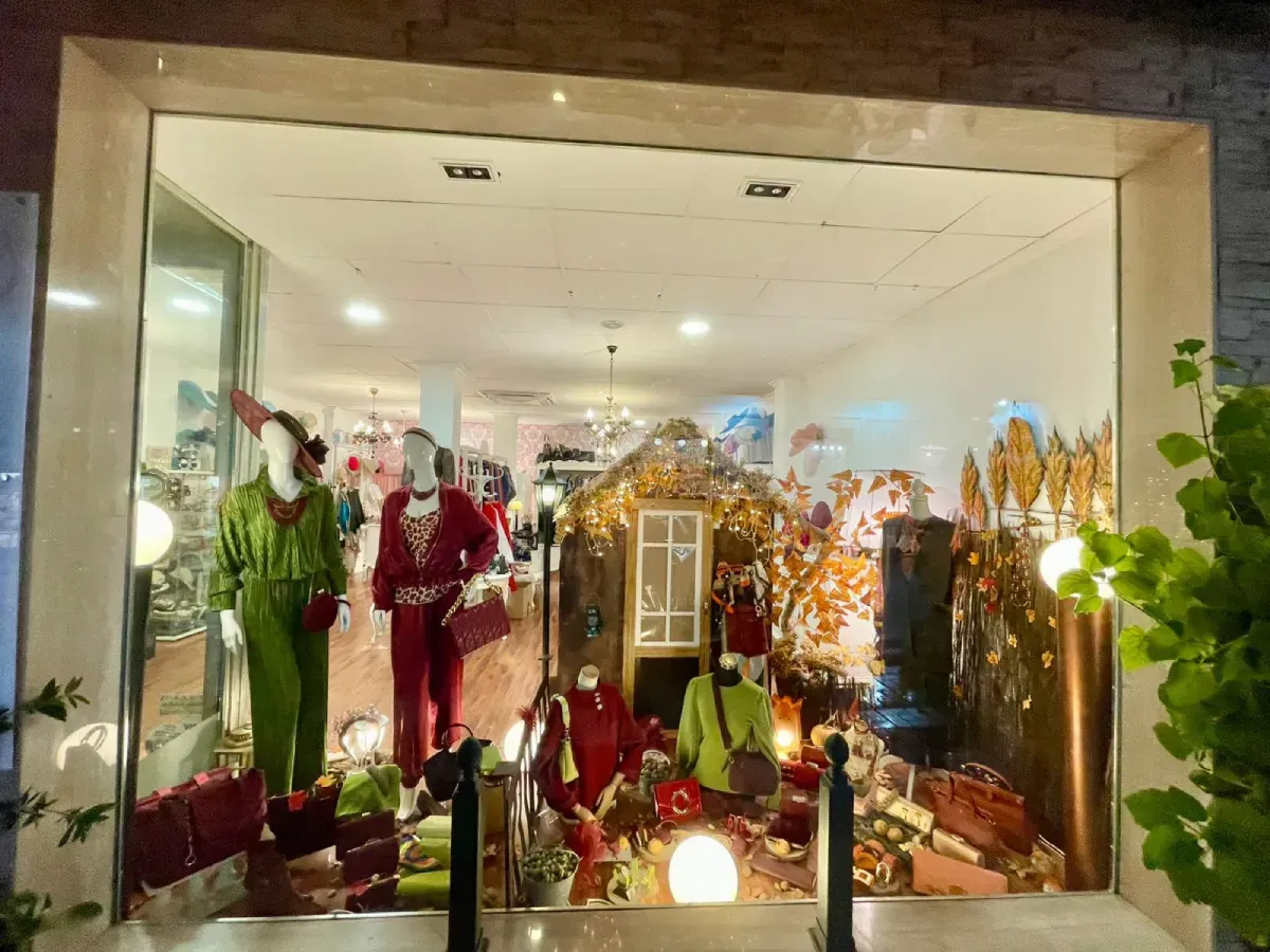 Escaparate de tienda con maniquíes con trajes de fiesta y una casa de jengibre.