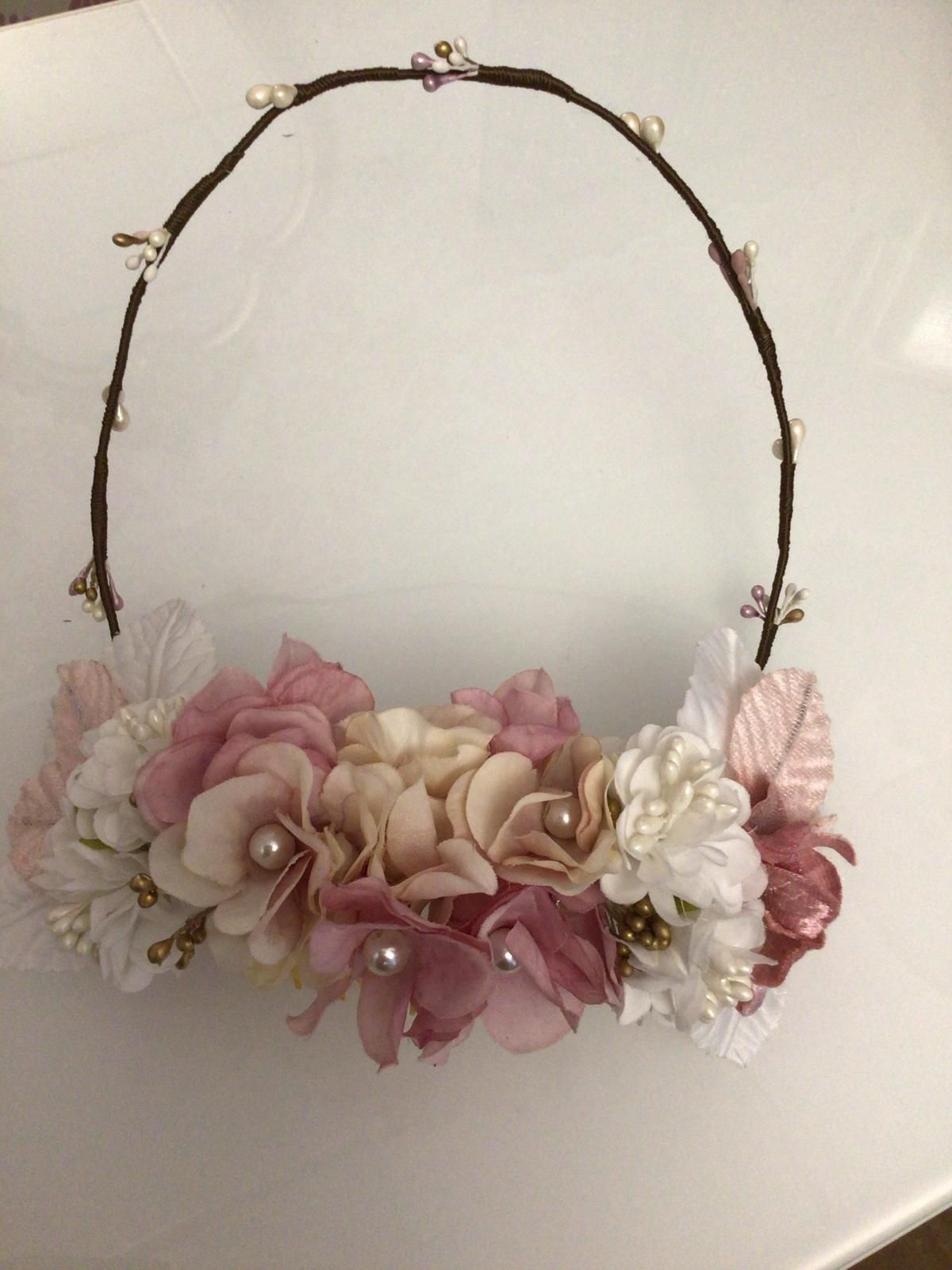 Corona de flores con flores rosas y blancas, perlas y alambre marrón.