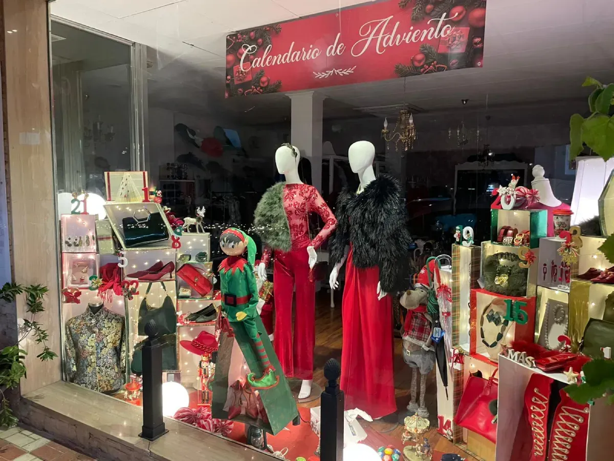 Escaparate de tienda con maniquíes vestidos de rojo, adornos navideños y un cartel que dice