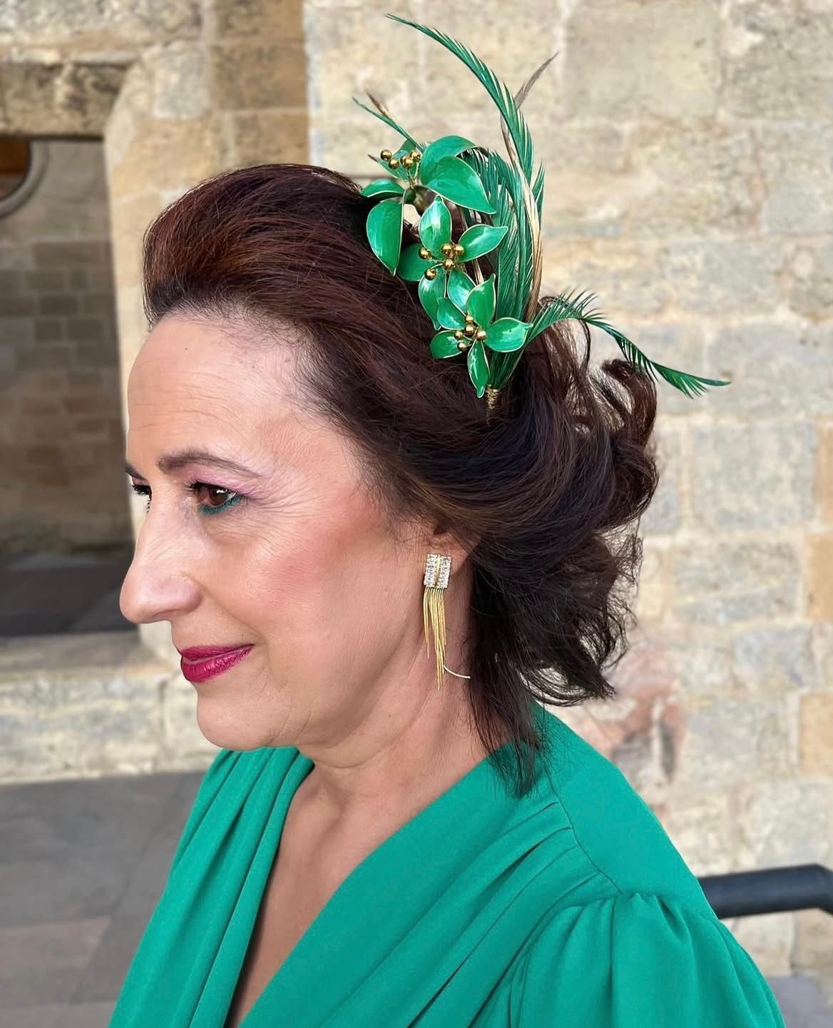Mujer de cabello oscuro, con tocado floral verde y vestido a juego.