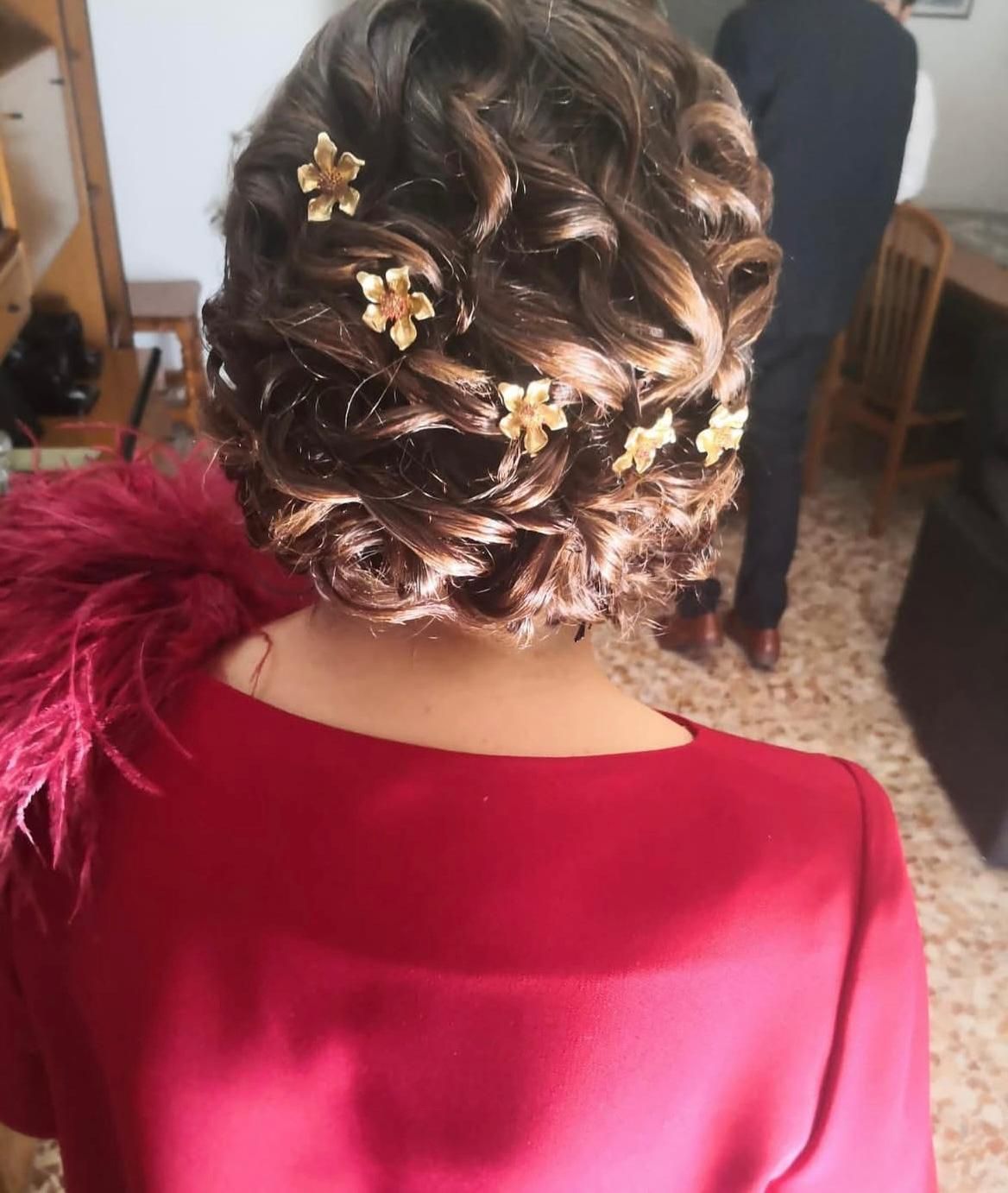 Mujer con peinado recogido, adornado con broches de flores doradas, luciendo un vestido rojo.