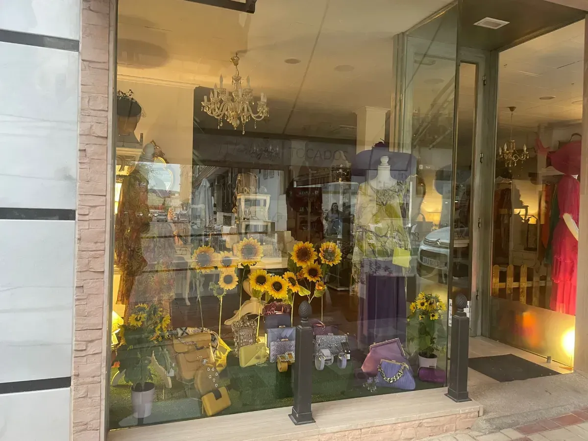 Escaparate con girasoles, vestidos y una lámpara de araña.
