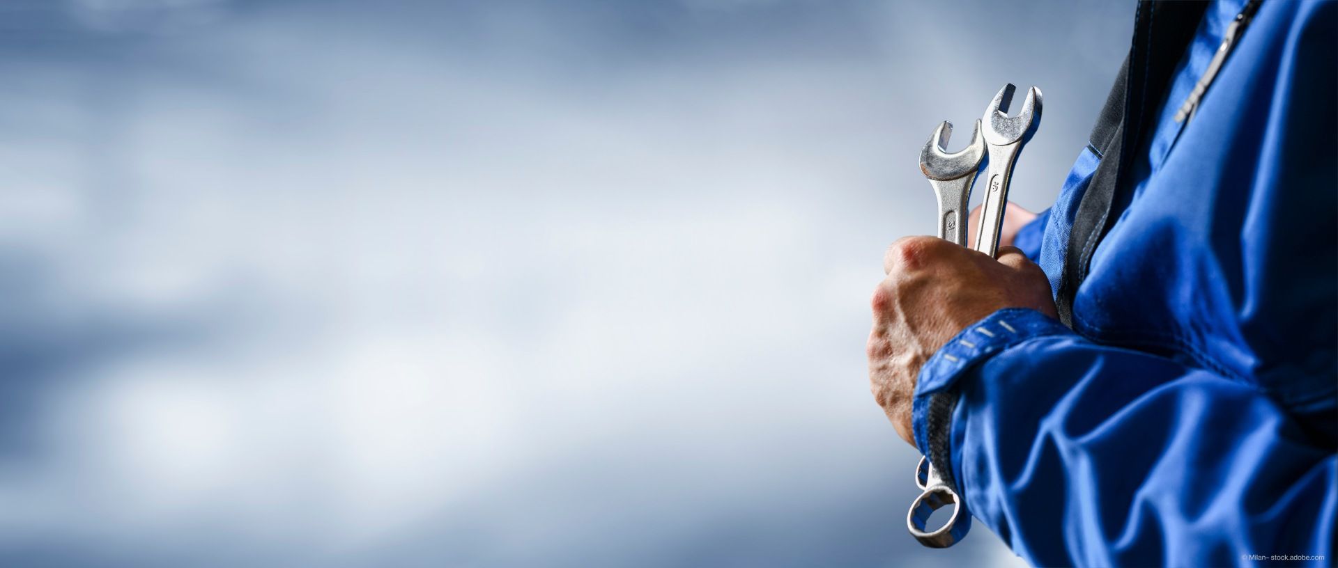 Handwerker im Blaumann mit Werkzeug in der Hand.