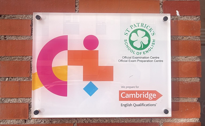 Letrero de evaluación de Cambridge en una pared de ladrillos con logotipo colorido y emblema circular verde