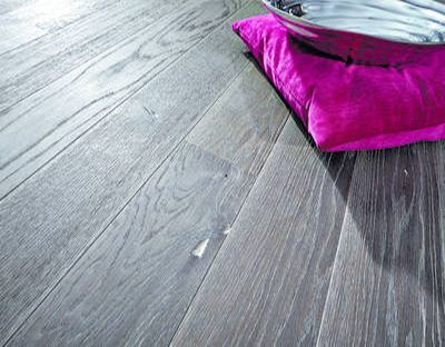 Ein rosa Kissen liegt neben einer Schüssel auf einem Holzboden.