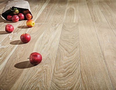 Ein Sack Äpfel steht neben einigen anderen Äpfeln auf einem Holzboden.