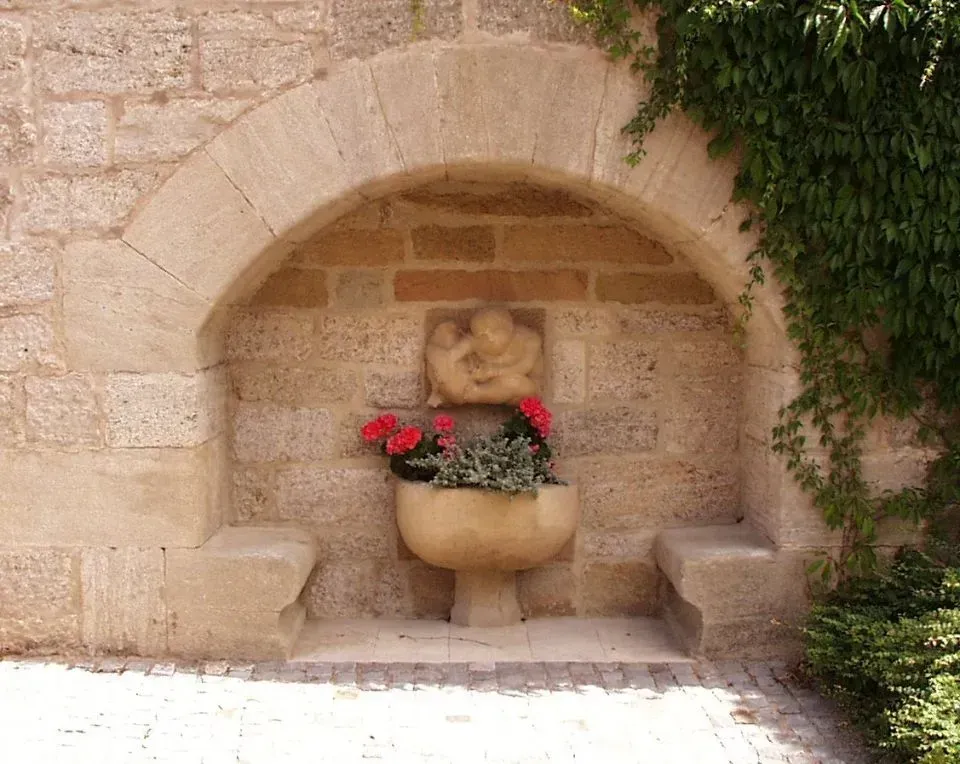 Eine Steinmauer mit einer Statue und einer Vase mit Blumen
