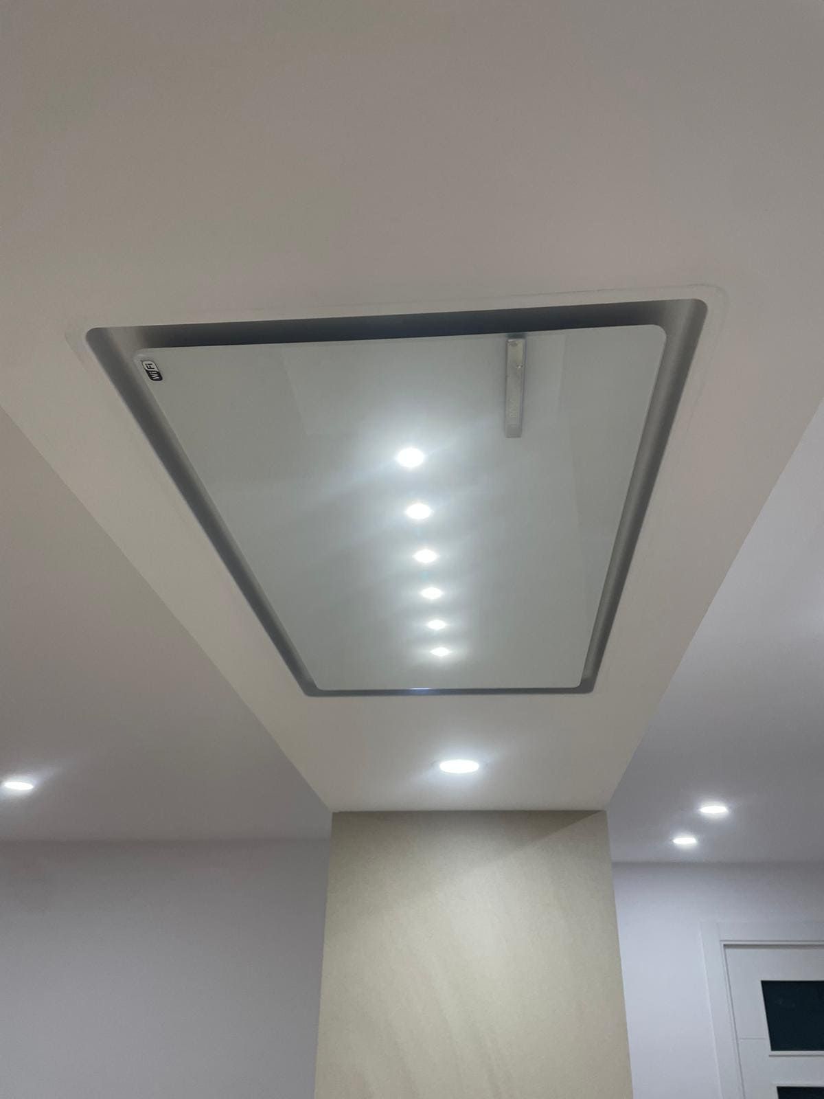 Trampilla de techo con vidrio esmerilado y luces empotradas en un interior moderno.