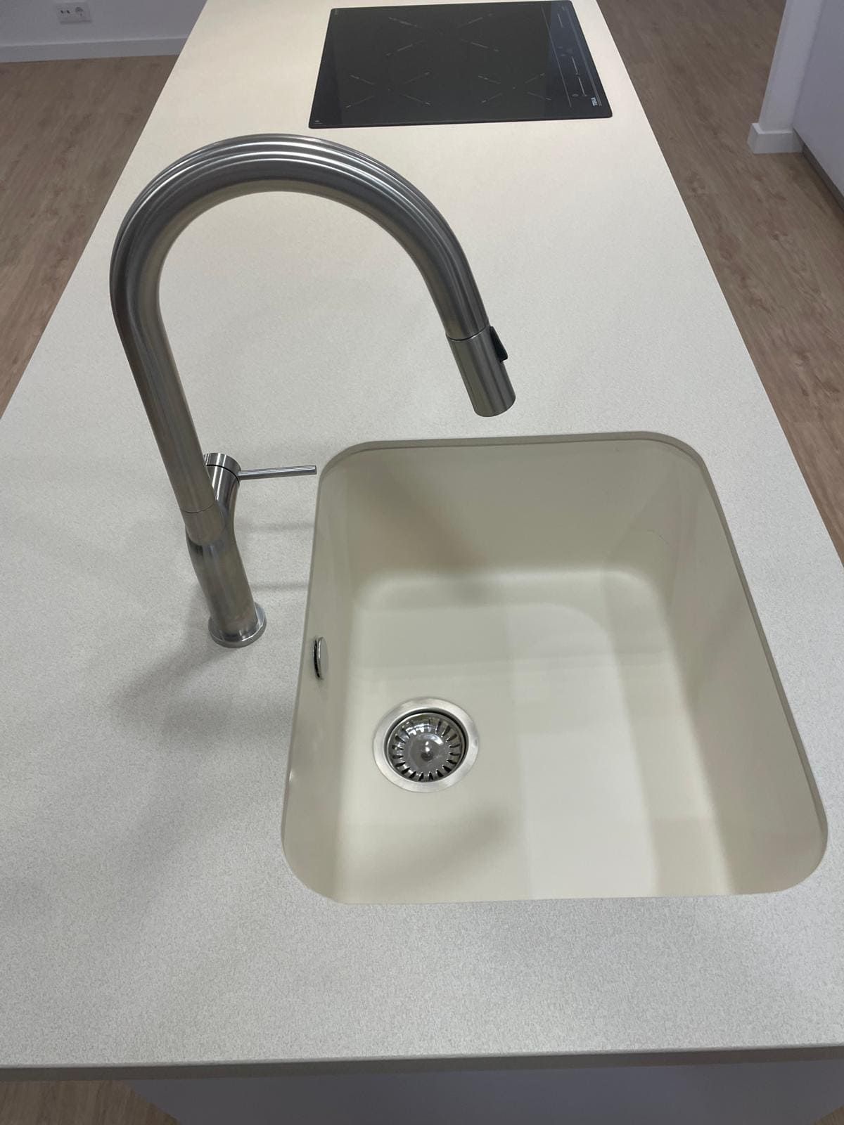 Encimera de cocina con grifo de acero inoxidable y fregadero blanco en un interior moderno.