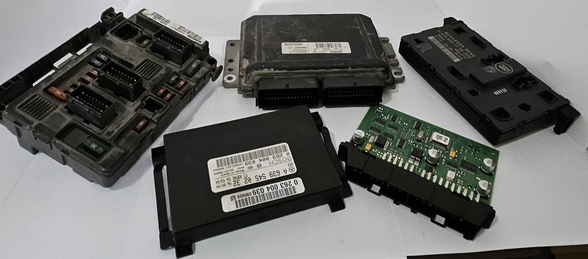 Varias unidades de control electrónico negras de un automóvil se muestran sobre una superficie blanca.