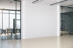 Intérieur de bureau moderne avec de grandes baies vitrées, des murs blancs et un éclairage lumineux.