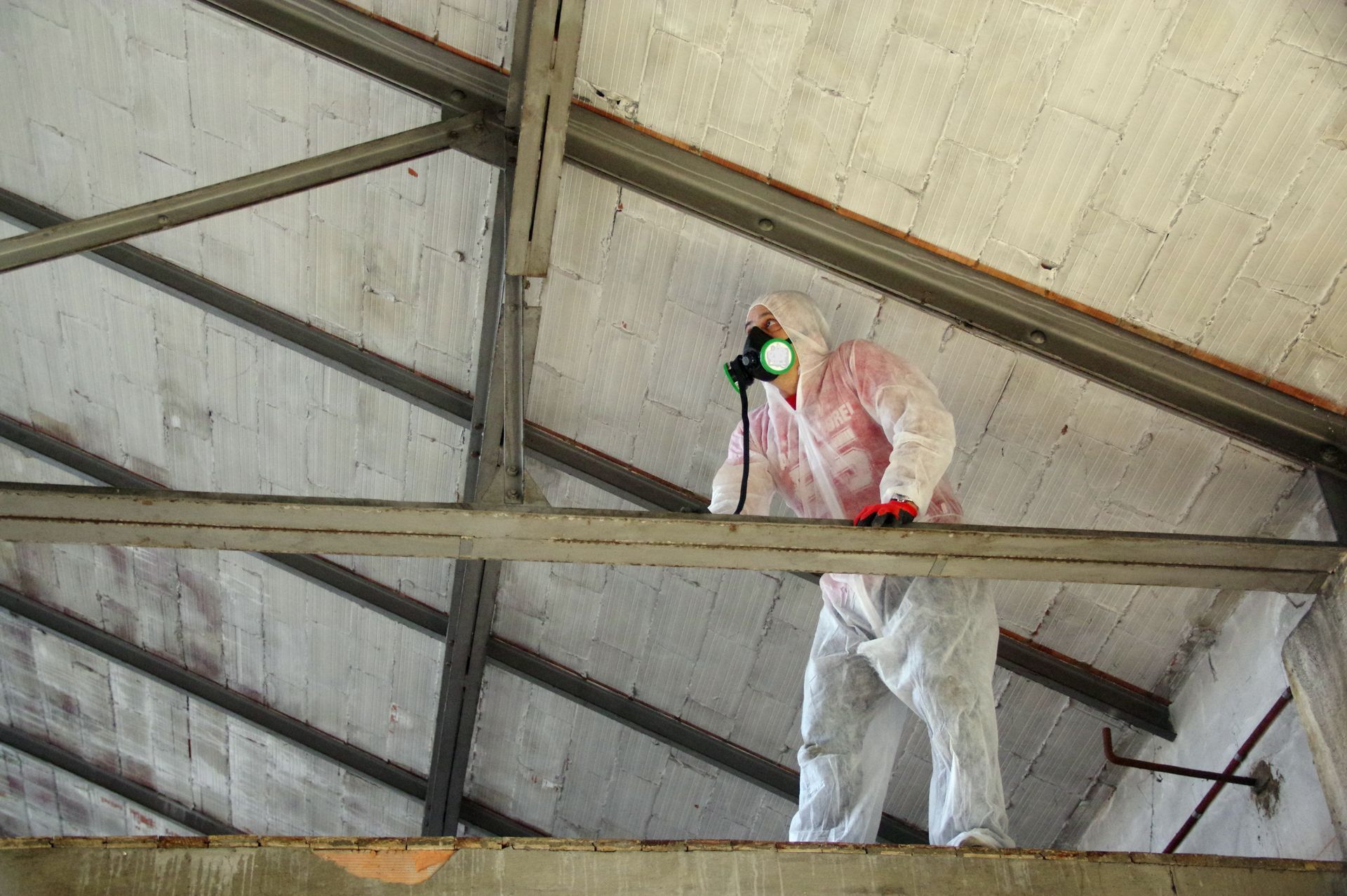 Une personne en combinaison de protection inspecte un plafond.