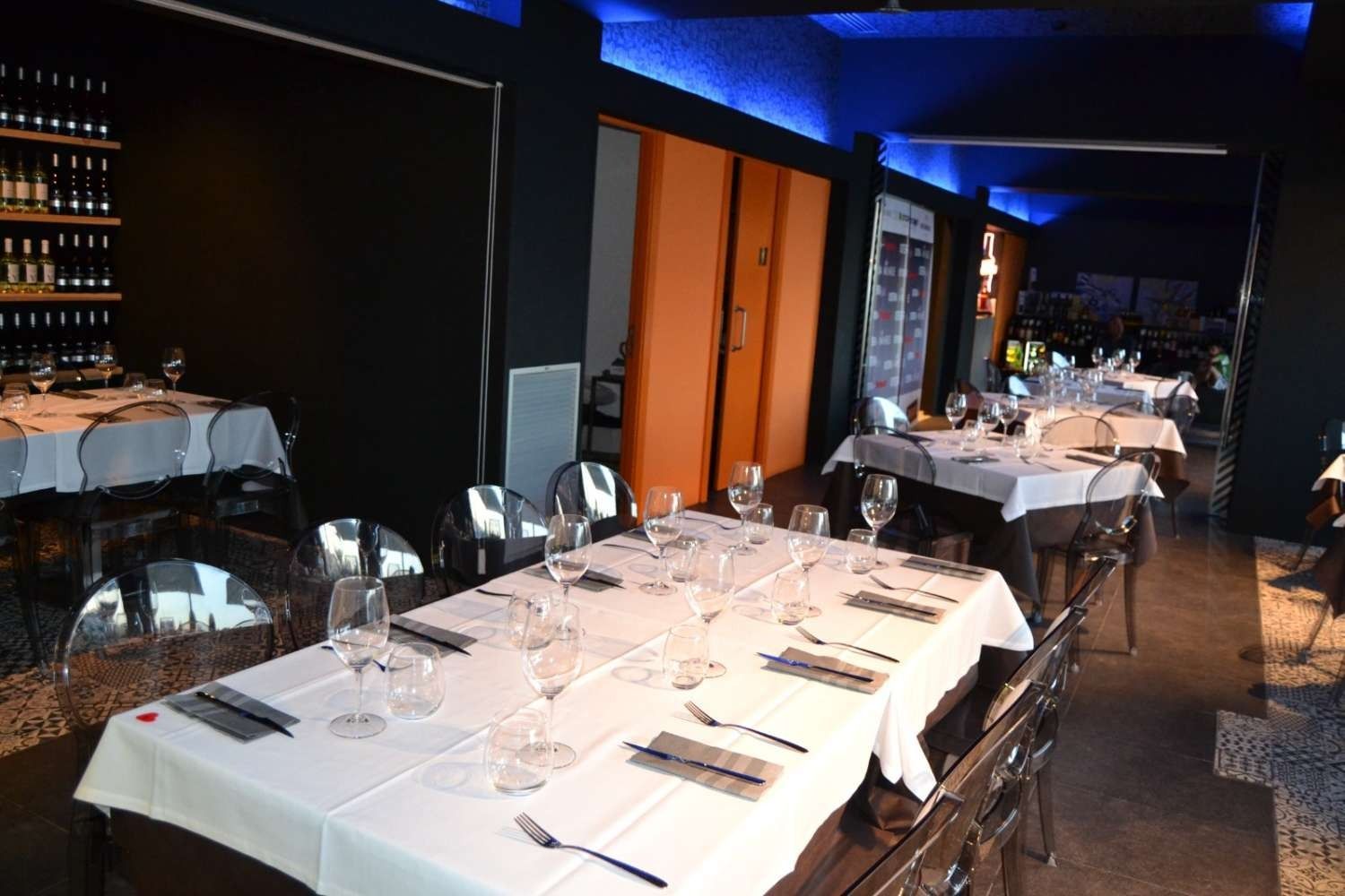 Un restaurante con mesas y sillas preparadas para una cena.