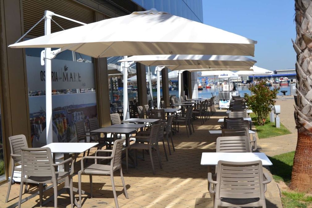 Un restaurante con mesas y sillas bajo sombrillas.