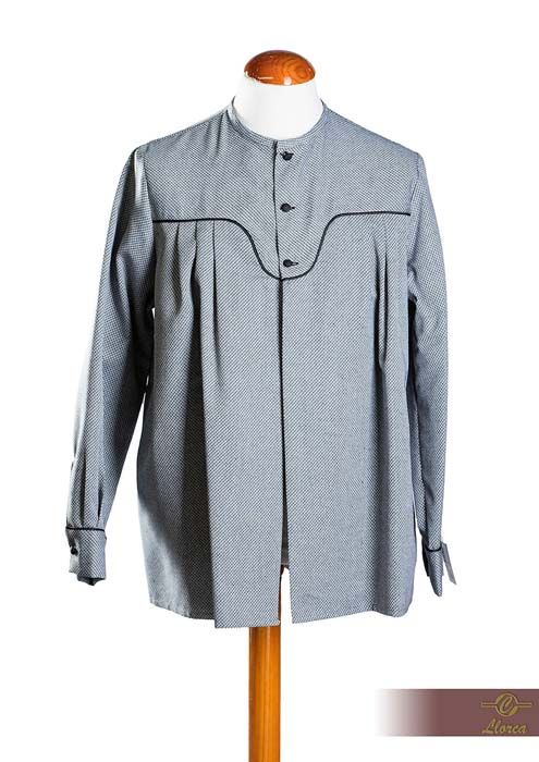 Una camisa de manga larga, de color azul claro estampado, con pechera delantera, canesú redondeado y tres botones, exhibida en un maniquí.