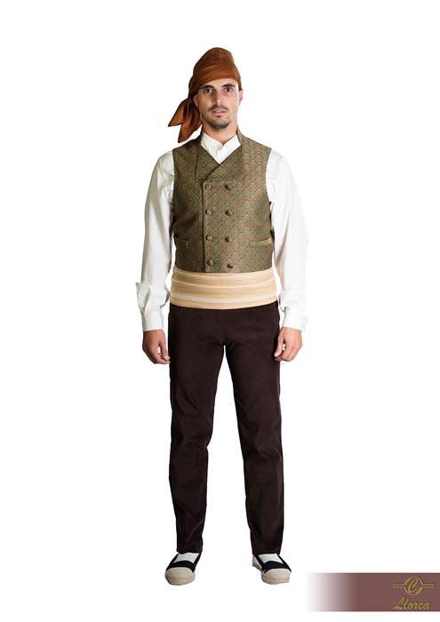 Una persona que viste una camisa blanca, un chaleco verde oliva estampado, una faja de color claro, pantalones oscuros, un pañuelo en la cabeza y alpargatas.