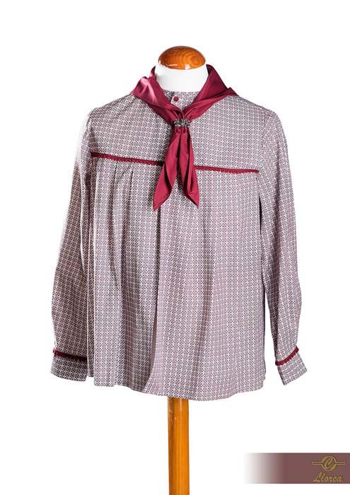 Blusa de manga larga y corte holgado con estampado en tonos morados y blancos apagados, adornada con un pañuelo y ribetes color burdeos.
