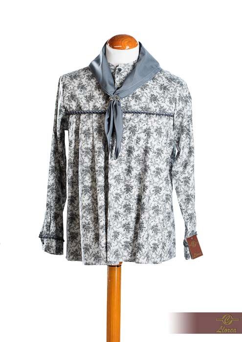 Una blusa de manga larga con estampado floral sobre un maniquí, combinada con una bufanda gris al cuello y detalles de ribete gris.