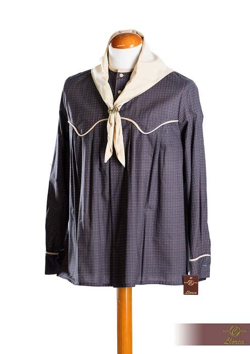 Una camisa azul marino oscuro abotonada con un estampado micro, ribete blanco y un pañuelo blanco al cuello en un maniquí.