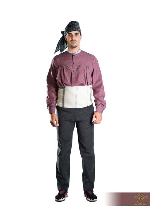 Una persona que lleva un pañuelo estampado en la cabeza, una camisa abotonada de color malva, un cinturón ancho blanco, pantalones oscuros y zapatos oscuros.