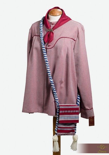 Una camisa roja a cuadros con una bufanda de cuello rojo oscuro y un bolso de hombro tejido y estampado con borlas en un maniquí.