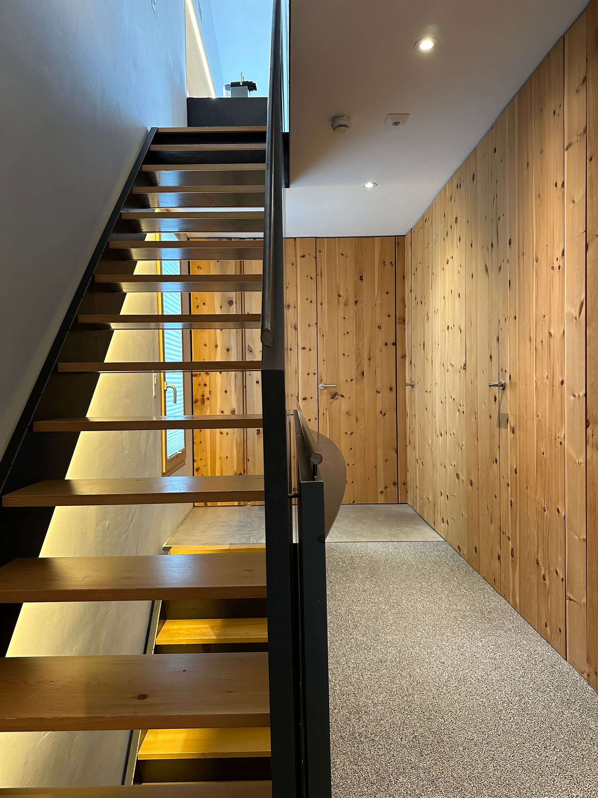 Moderne offene Treppe Stahltreppe mit Holzverkleidung im Ferienhaus Buna Saira in Scuol in der Schweiz 