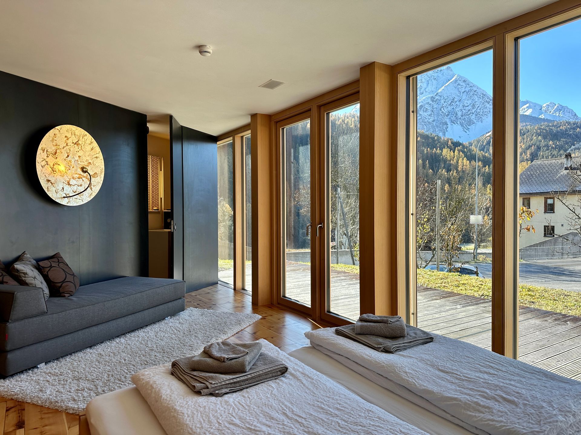 Schlafzimmer im Ferienhaus Buna Saira in Scuol mit bodentiefen Fenstern, Bergblick, Terasse und ensuite Badezimmer