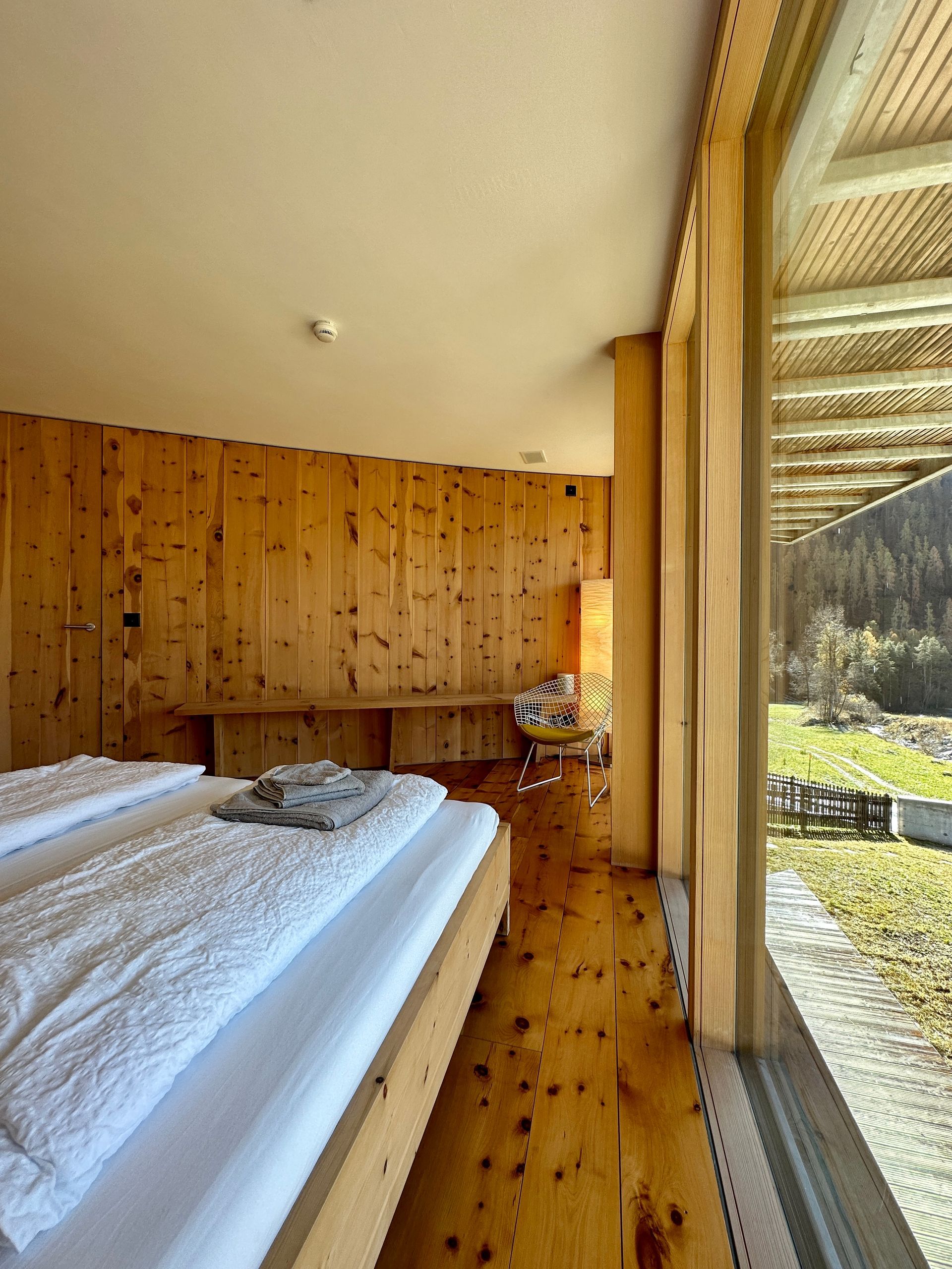 Schlafzimmer im Ferienhaus Buna Saira in Scuol mit hochwertiger Holzverkleidung und Ausblick 