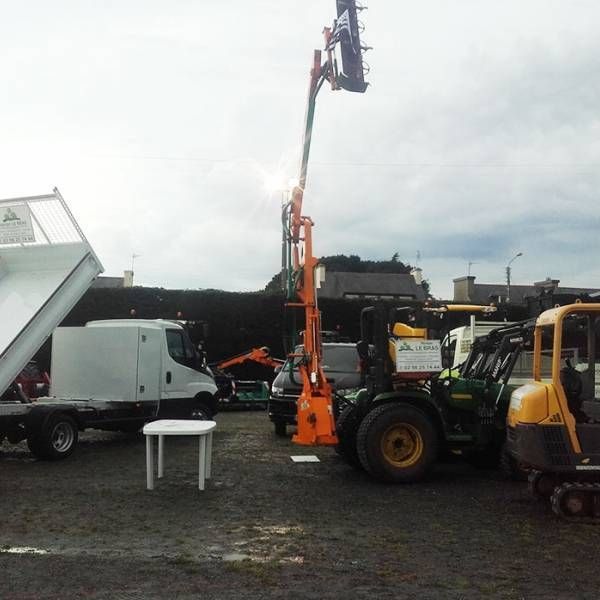 Chantier avec un camion blanc, une nacelle articulée orange et une excavatrice jaune sur un terrain boueux