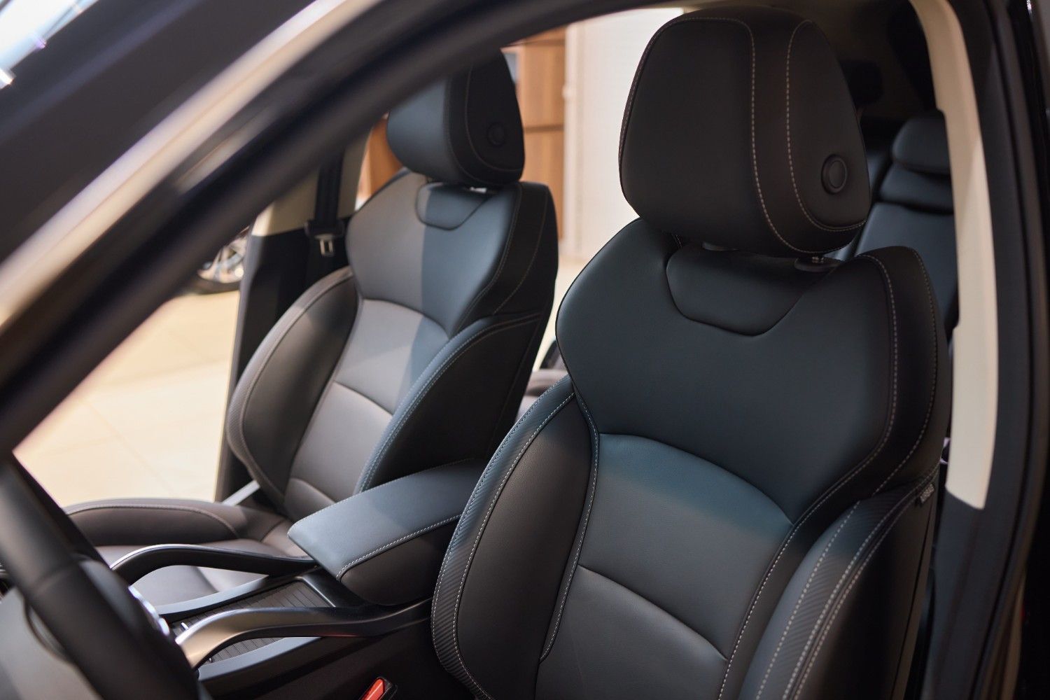 El interior de un vehículo con asientos deportivos de cuero negro con costuras blancas y reposacabezas integrados.