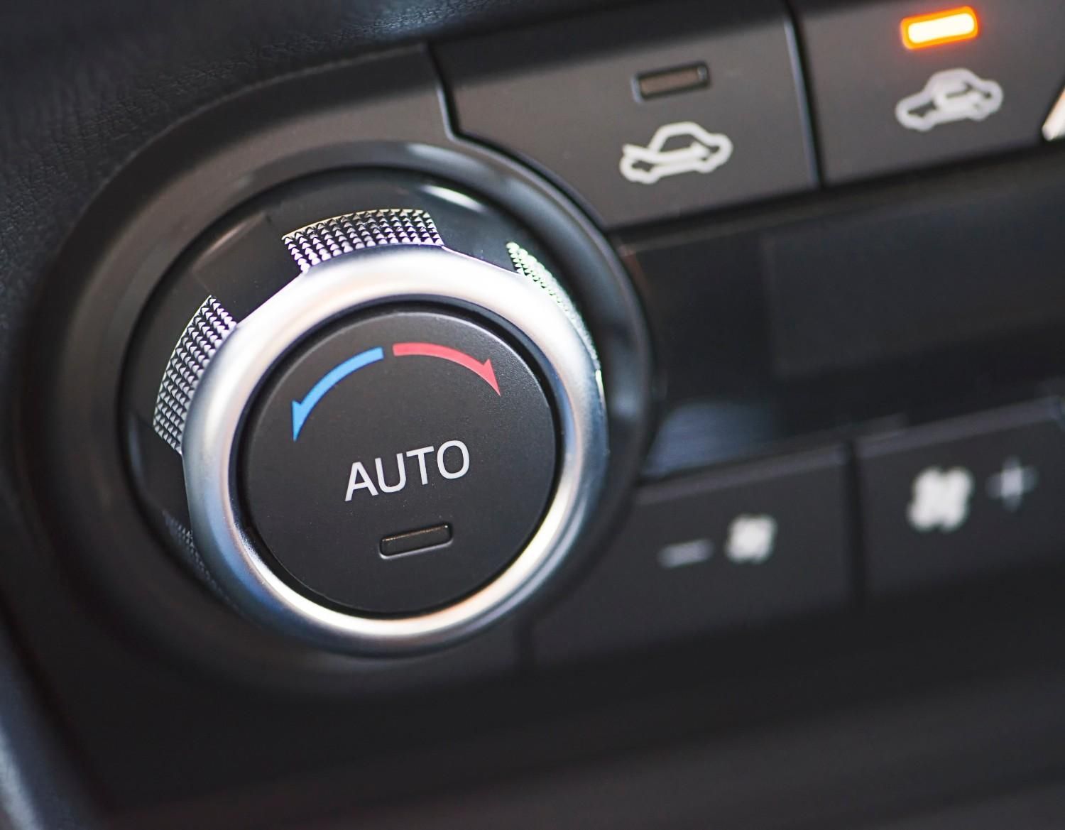 Primer plano del selector del climatizador de un coche, etiquetado como 