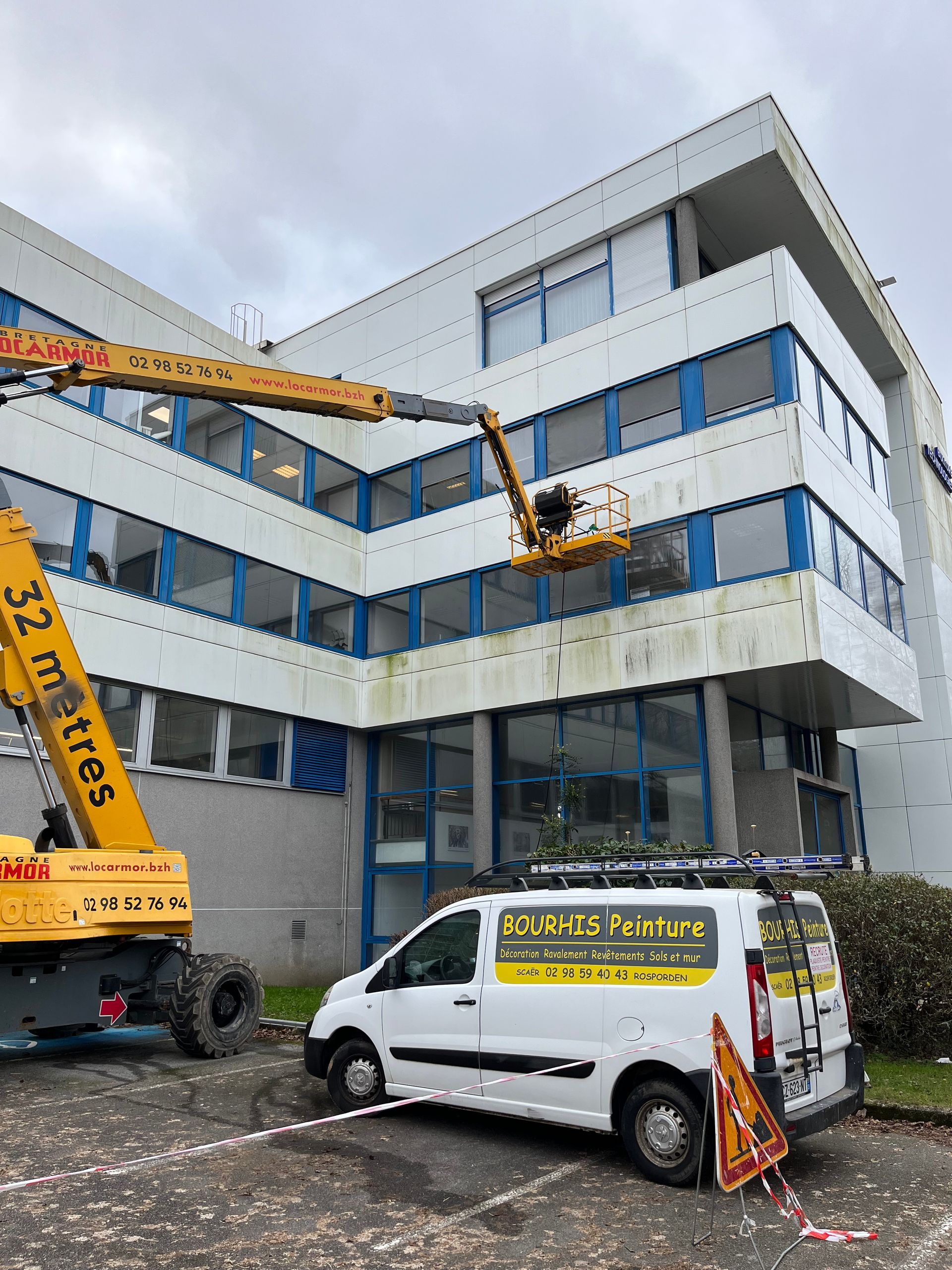 Un ouvrier sur une nacelle qui nettoie une façade