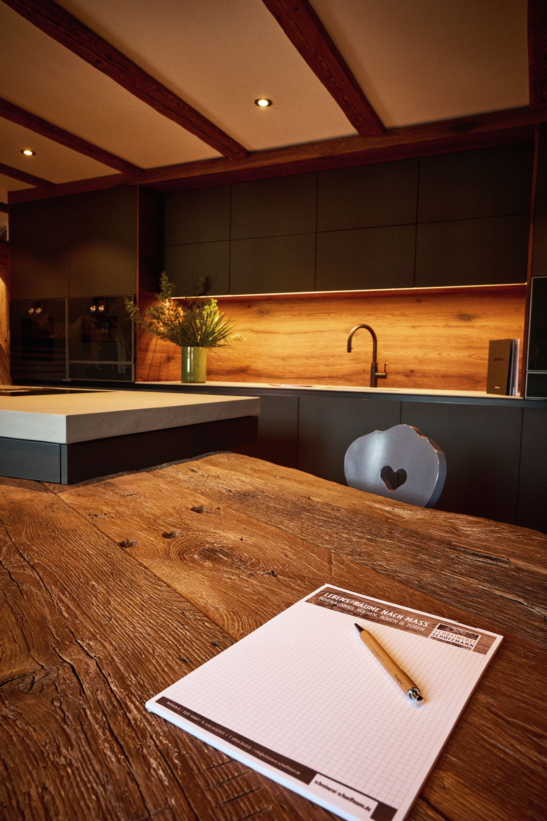 Detailaufnahme: Minimalistische, grifflose Küche mit matten schwarzen Fronten und Holzarbeitsfläche