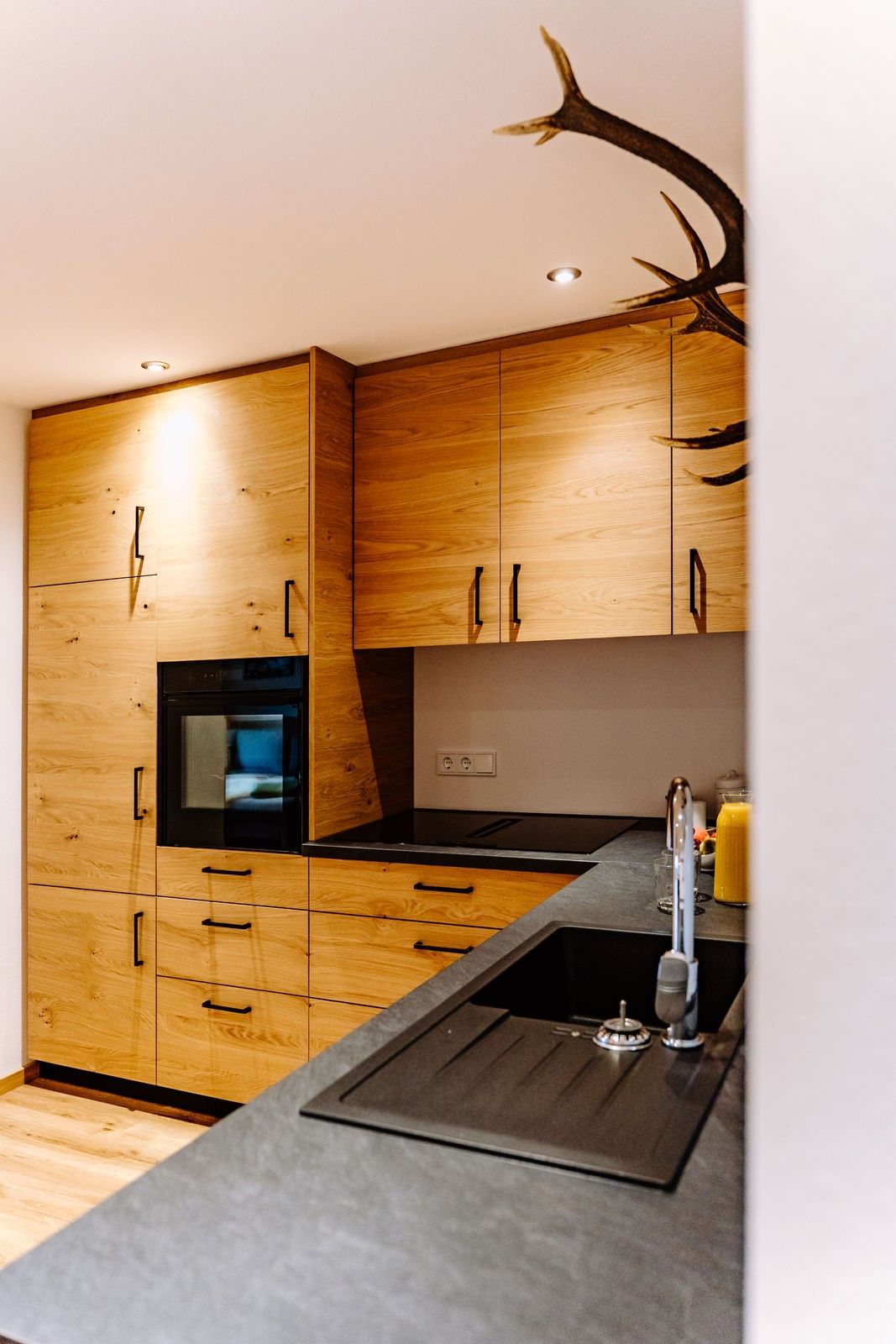 Küche mit Holzfronten und schwarzen Griffen, eingebauter Backofen