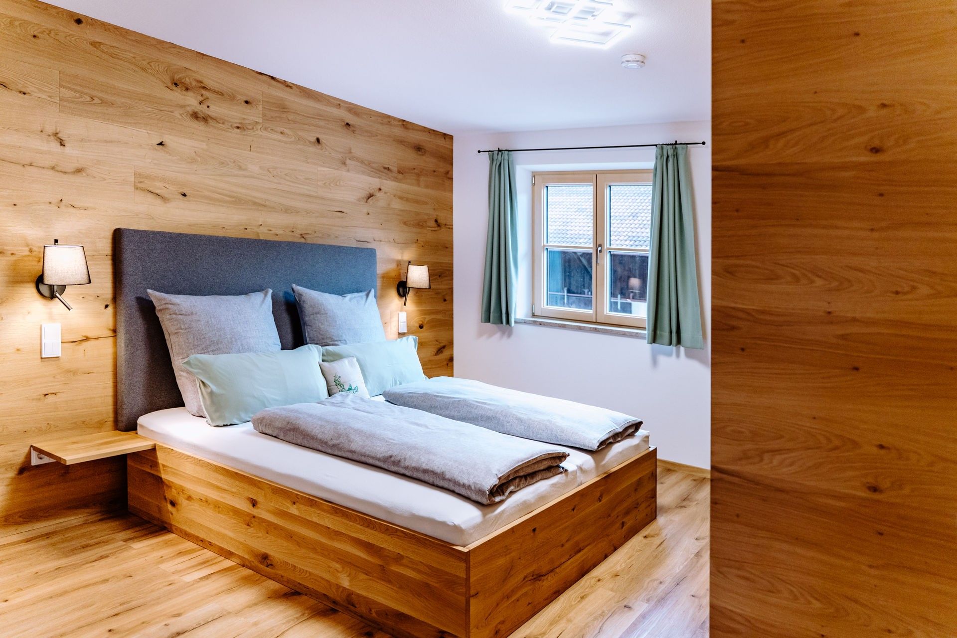 Modern rustikales Bett aus Holz mit Holzvertäfelung an der Wand und schwebenden Holznachttischen