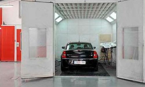 Un coche está estacionado dentro de una cabina de pintura.