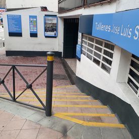 Una escalera que conduce a un edificio con un cartel azul que dice talleres jose luis s.