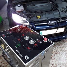 Un automóvil con el capó levantado y un panel de control delante.