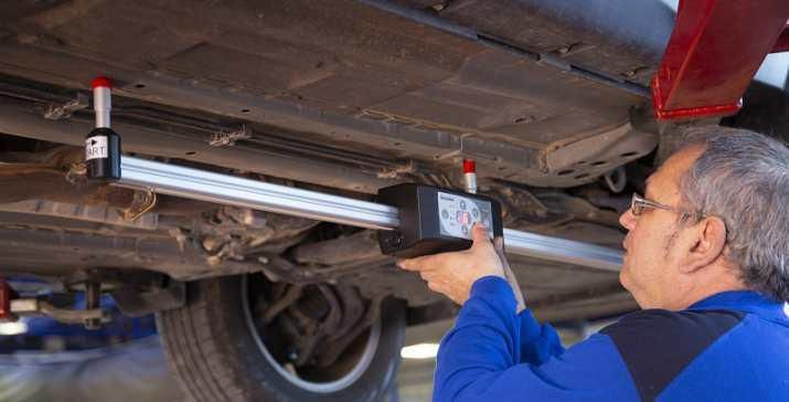 Un hombre está trabajando en la parte inferior de un coche en un garaje.