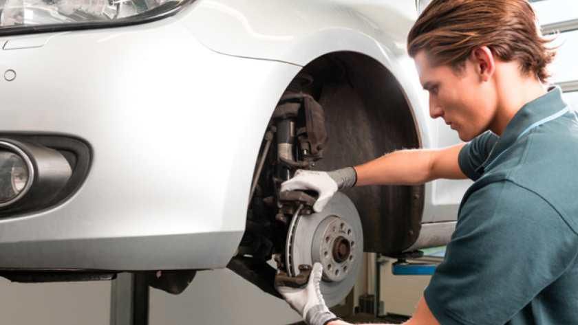 Un hombre está trabajando en las pastillas de freno de un coche.