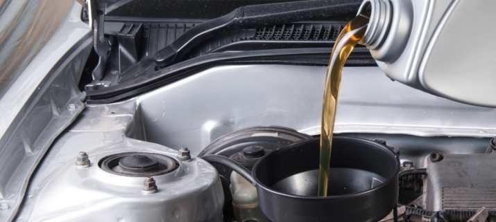 Una persona está echando aceite en el motor de un coche.
