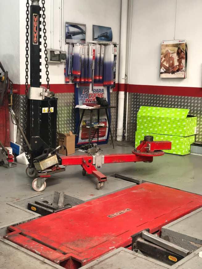 Un ascensor rojo está estacionado en un garaje al lado de un sofá verde.