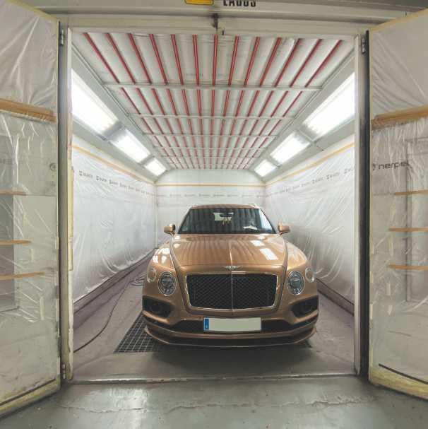 Un coche está aparcado dentro de una cabina de pintura.