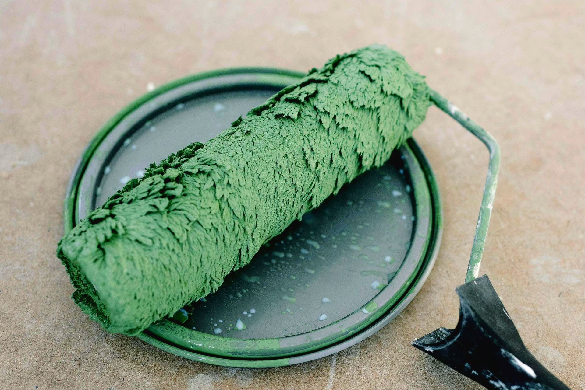 Un rodillo de pintura verde está sobre una placa negra