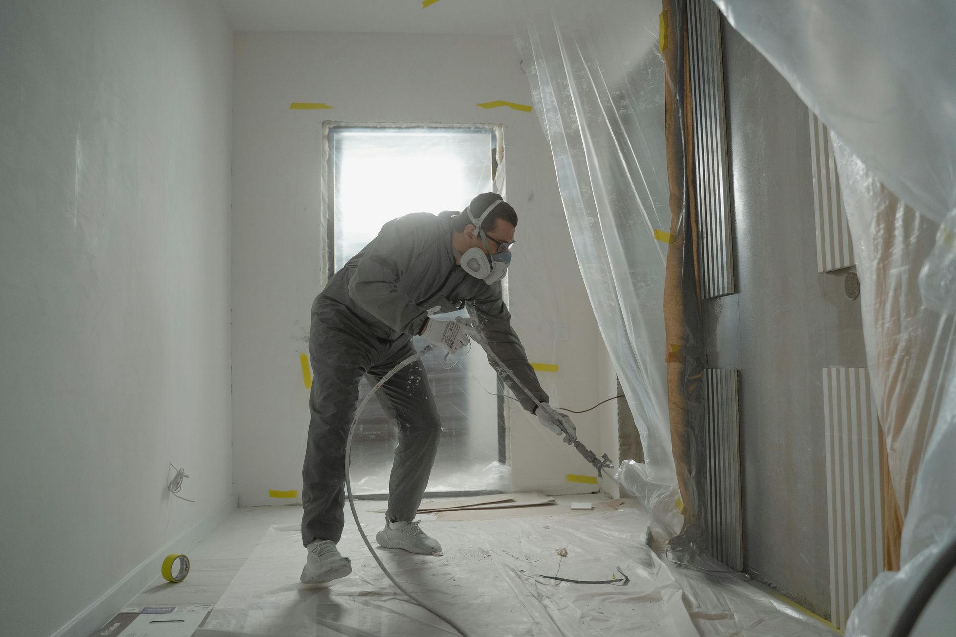 Un hombre que lleva una máscara está pintando con aerosol una pared en una habitación.